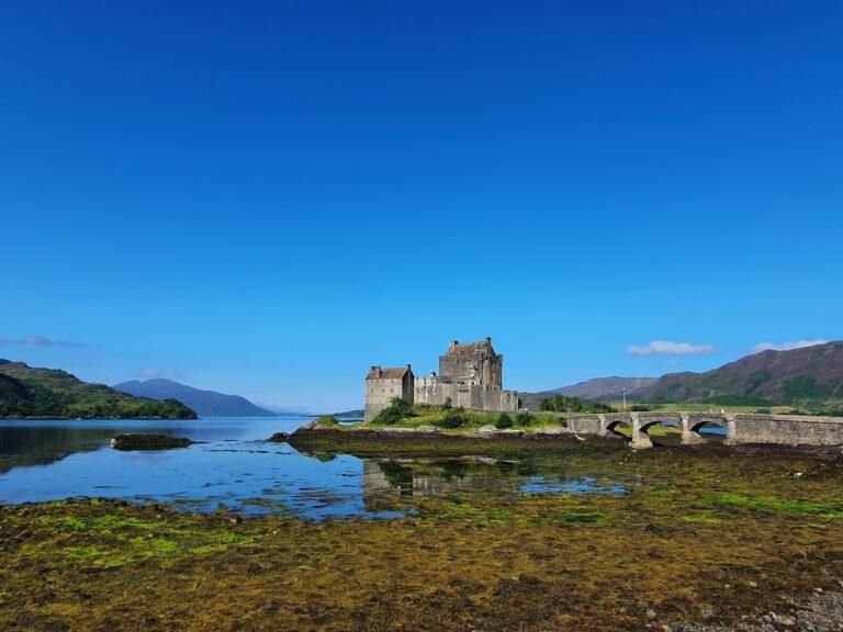Eilean Donan Castle in the Scottish Highlands, Scotland, reflected in calm waters.